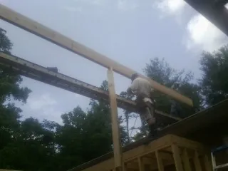 Carpenter setting a ridge beam over a new addition frame — Ice Dam Removal by Roofing Brothers in Reinholds