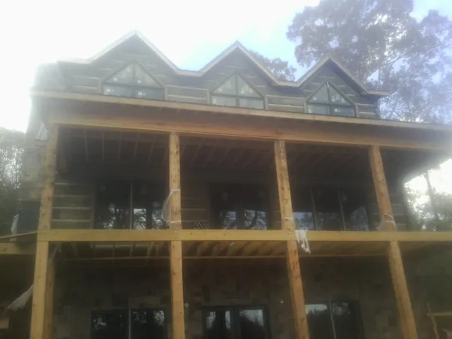 Dormers and porch framing on a large log home under construction — Roof Coating work by our crew in Reinholds