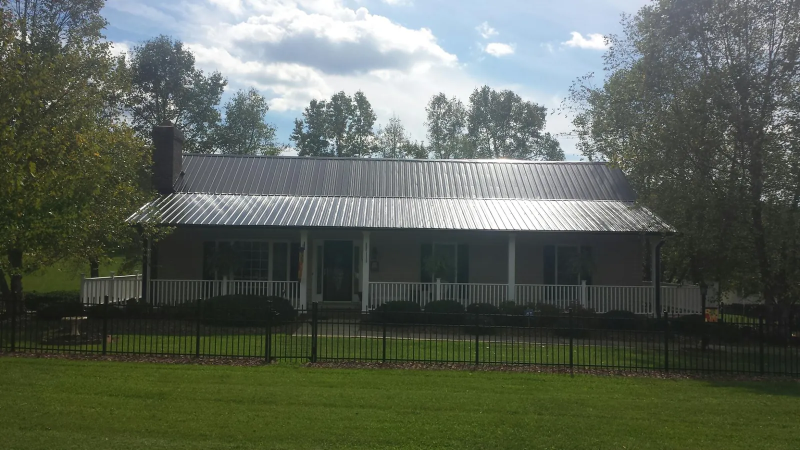 Gray metal roof on a brick ranch with a full width front porch — Gutter Guard Installation work by our crew in Reinholds