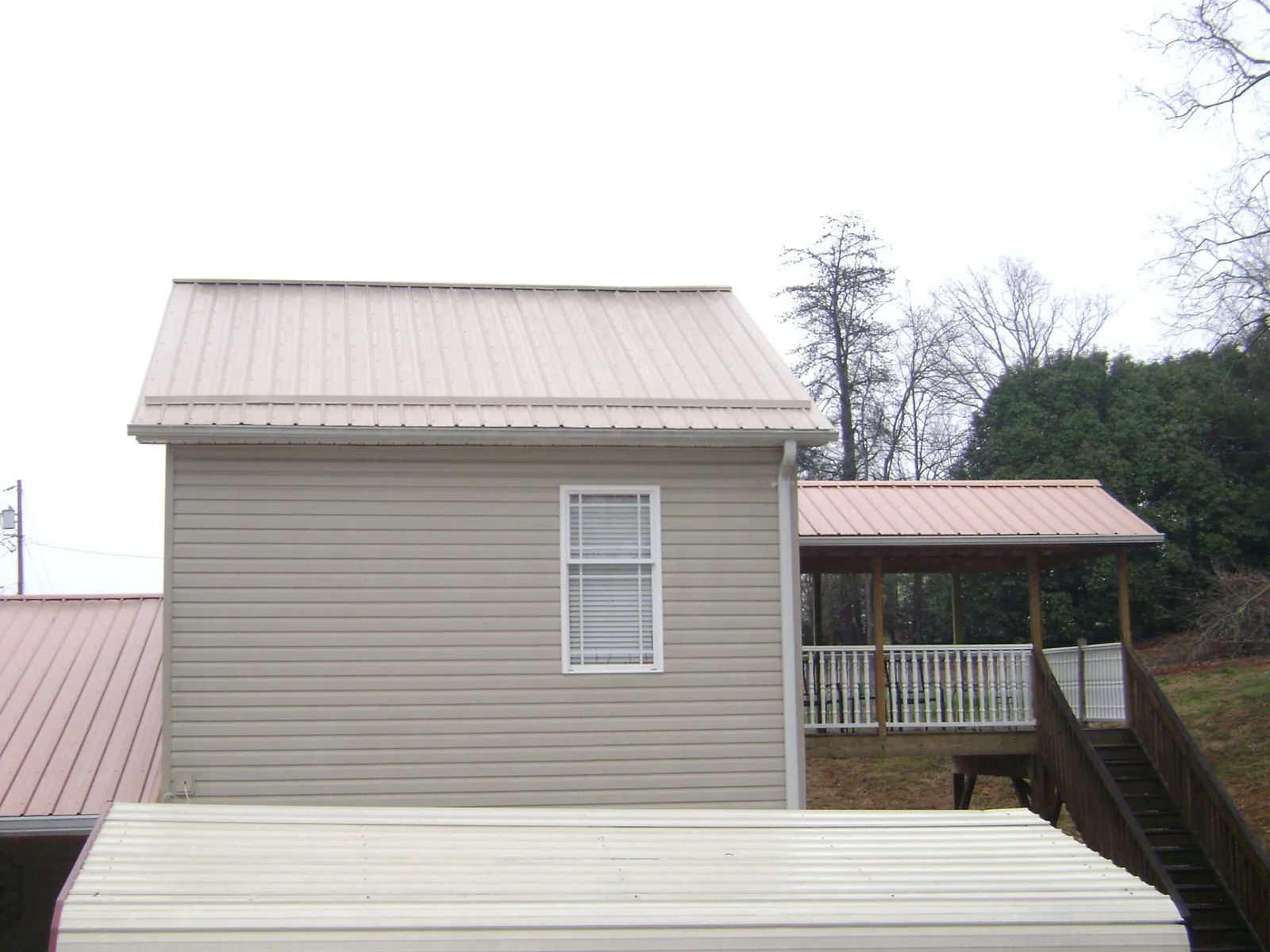 Tan metal roofs on a two story addition and attached porch, from a Roof Replacement job in Reinholds