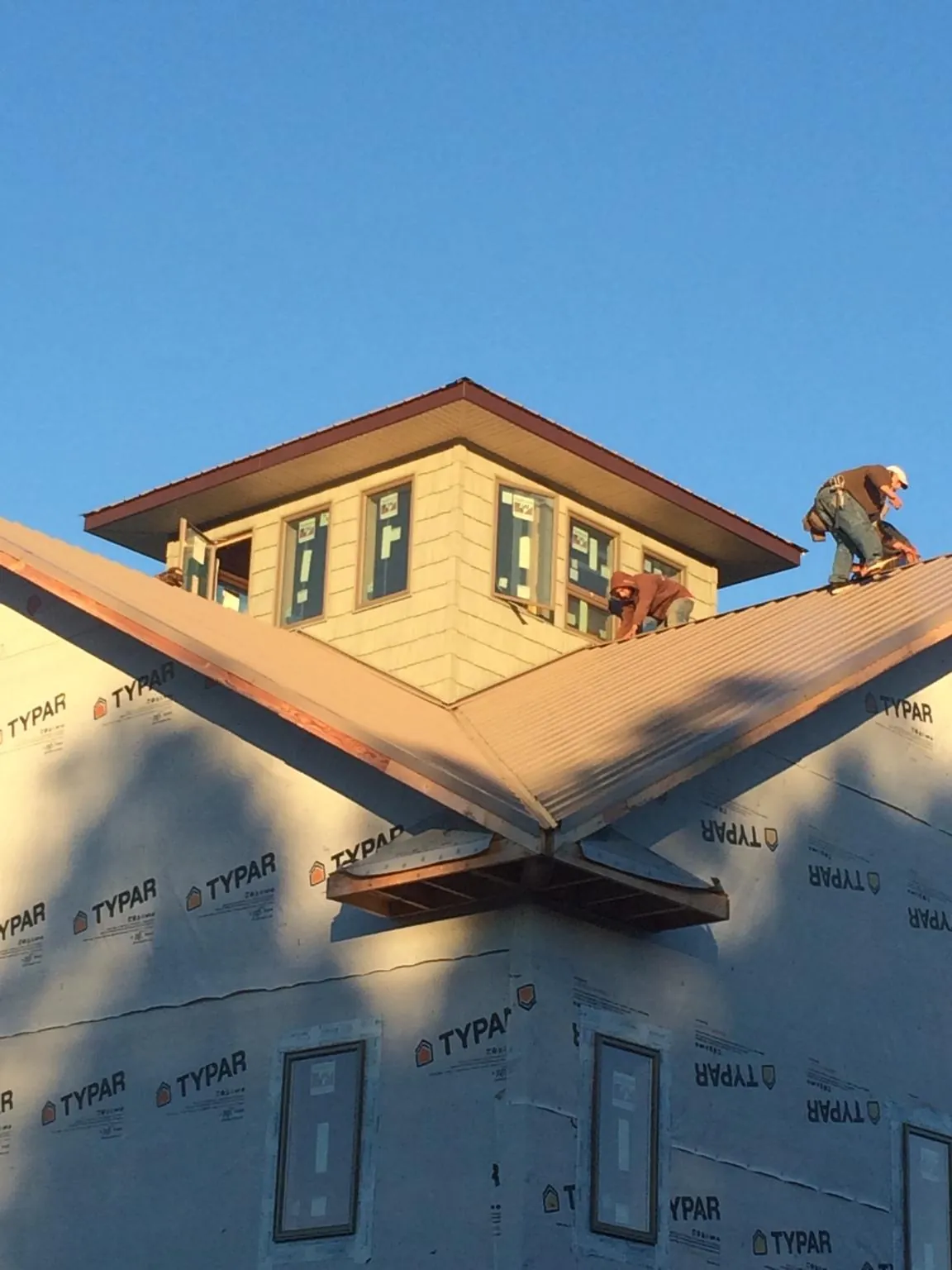 Roofers working around a rooftop cupola on a new metal roof at sunset — Roof Waterproofing in Reinholds by Roofing Brothers